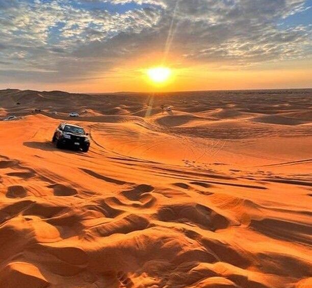 Luxury 4x4 vehicle during a premium desert safari Dubai with golden sand dunes, a camel ride, and a sunset desert camp experience.